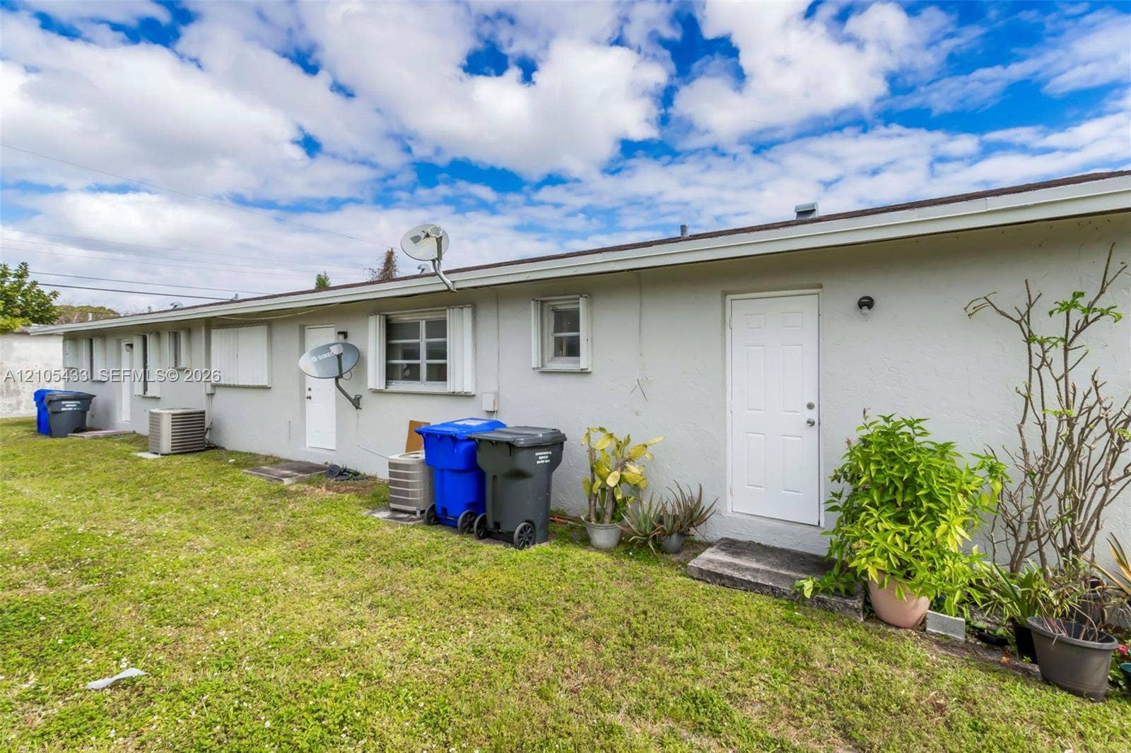 6331 Pierce Street, #1, Hollywood, Hollywood, FL 33024 Expansive grassy area with concrete patio, multiple entry points, and central air conditioning units