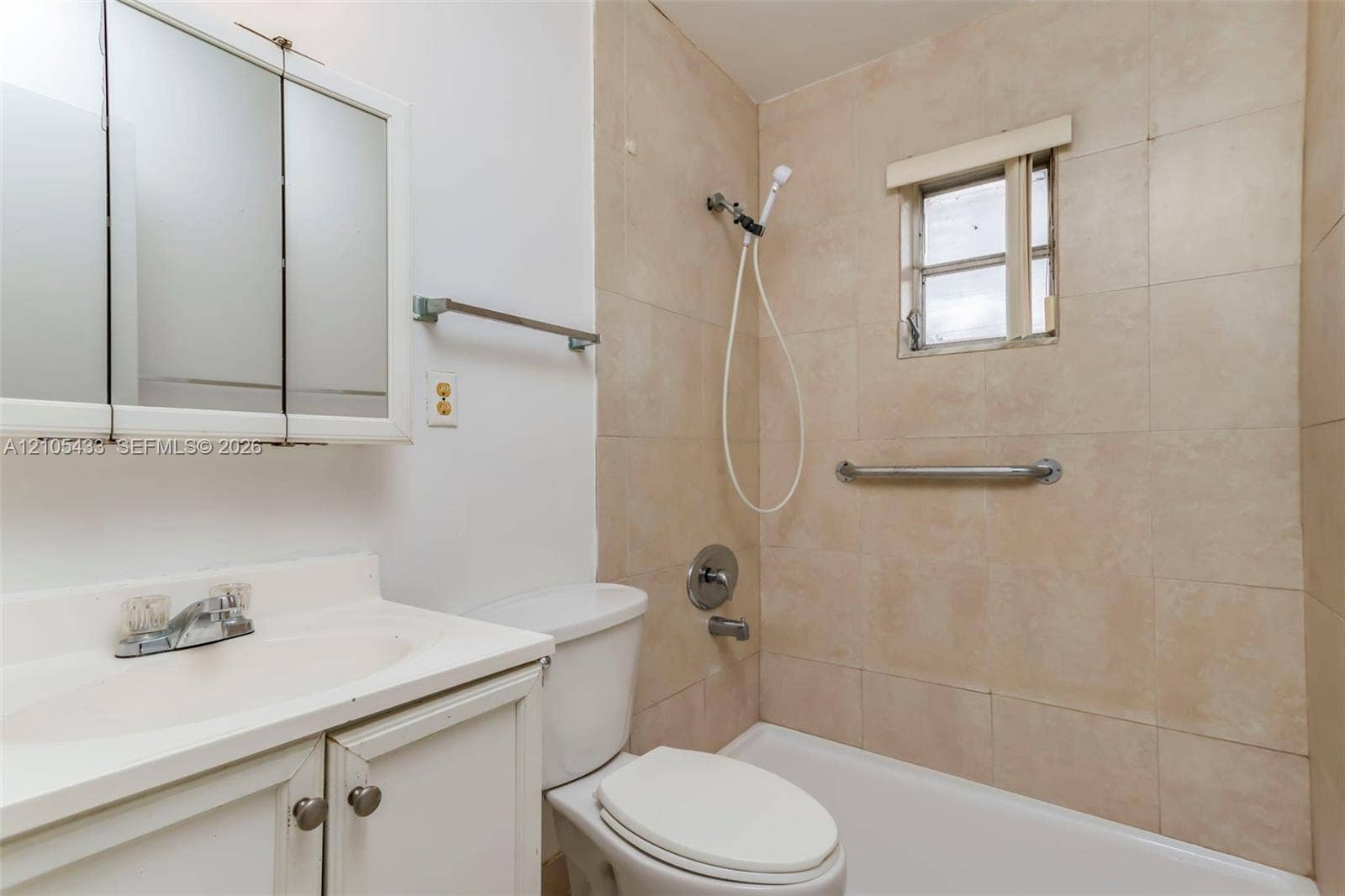 6331 Pierce Street, #1, Hollywood, Hollywood, FL 33024 White vanity with integrated sink, tri-fold mirrored medicine cabinet, white toilet, and tiled shower surround with grab bar