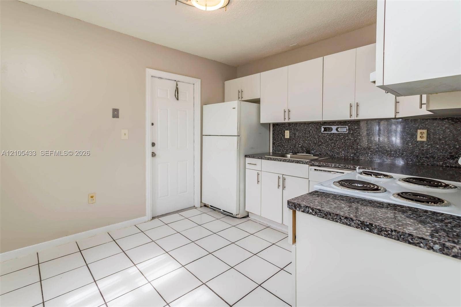 6331 Pierce Street, #1, Hollywood, Hollywood, FL 33024 Kitchen featuring white cabinetry, dark speckled countertops, white tile flooring, and a white refrigerator