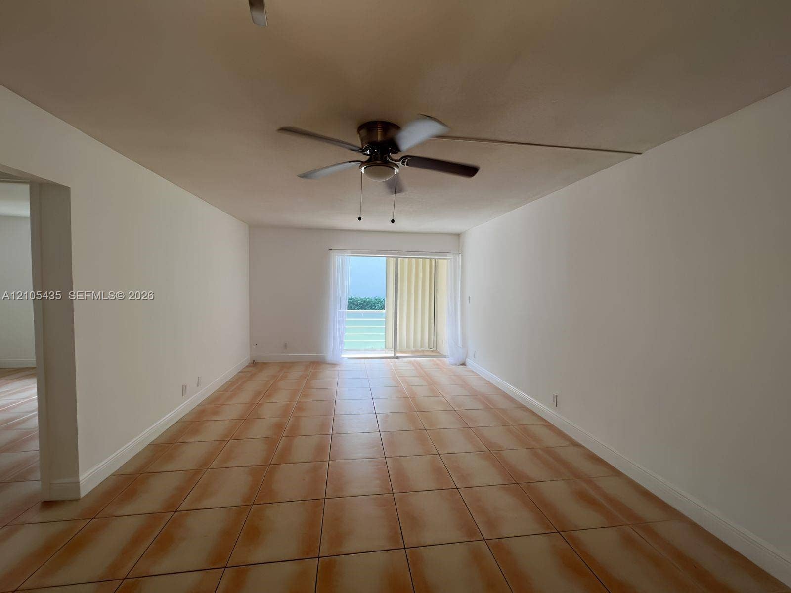 1428 SE 4th Avenue, #159, Deerfield Beach, FL 33441 Neutral-toned interior space featuring ceramic tile flooring, a mounted ceiling fan, and sliding glass doors