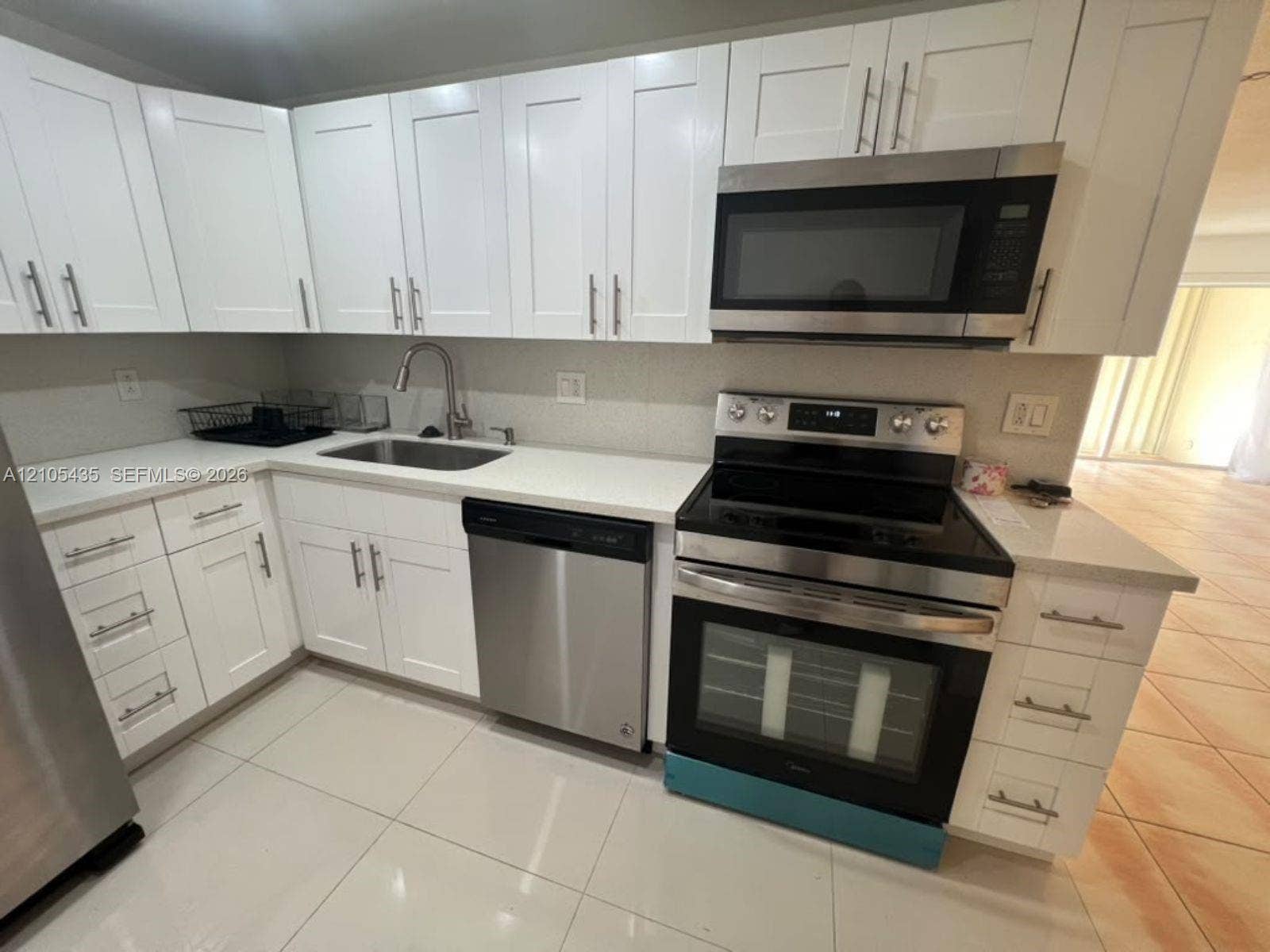 1428 SE 4th Avenue, #159, Deerfield Beach, FL 33441 Kitchen featuring white shaker-style cabinetry, solid-surface countertops, stainless steel appliances, and tile flooring