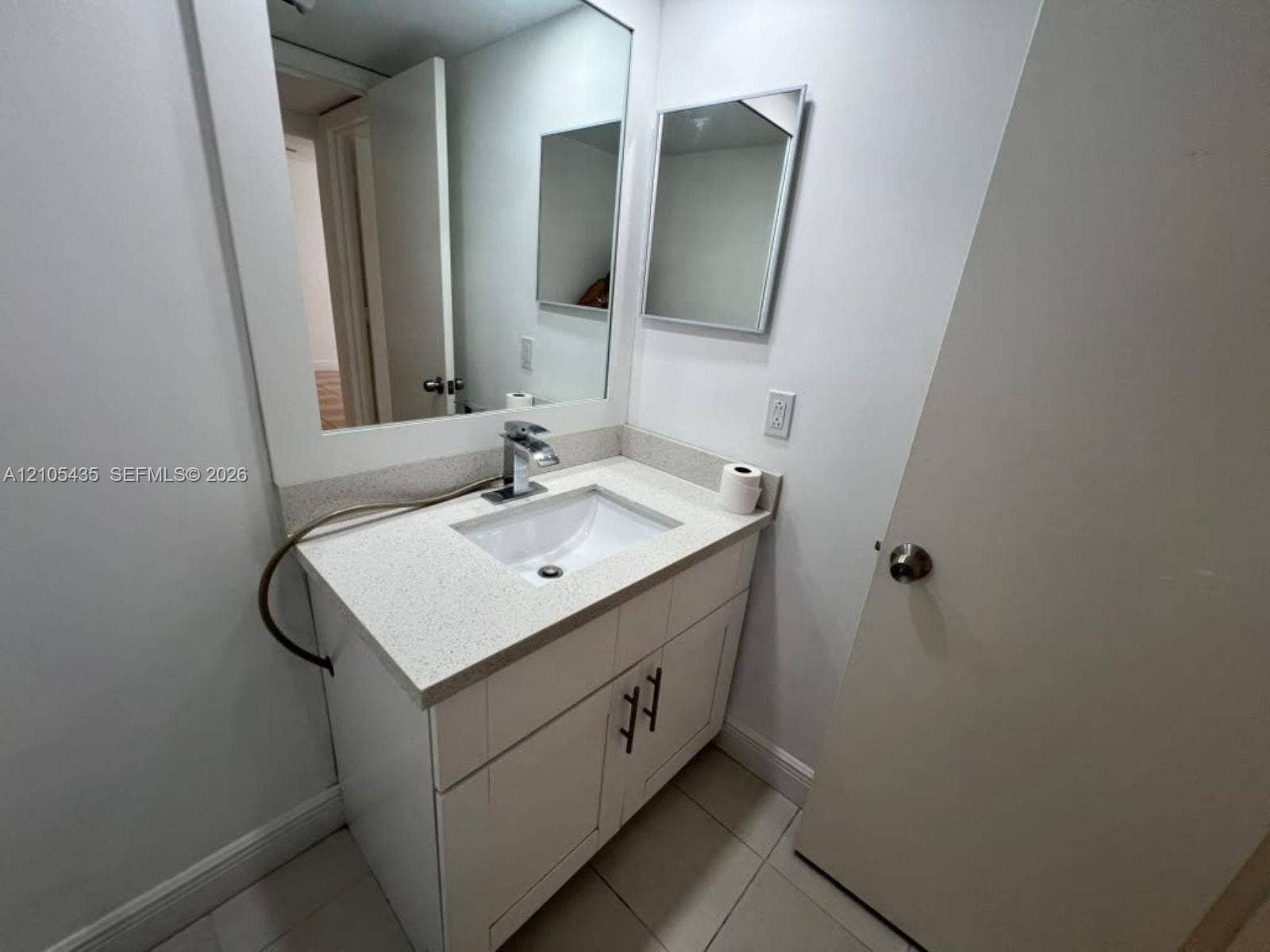 1428 SE 4th Avenue, #159, Deerfield Beach, FL 33441 White vanity cabinet with shaker-style doors, stone-composite countertop, undermount sink, polished chrome faucet, and rectangular wall-mounted mirror