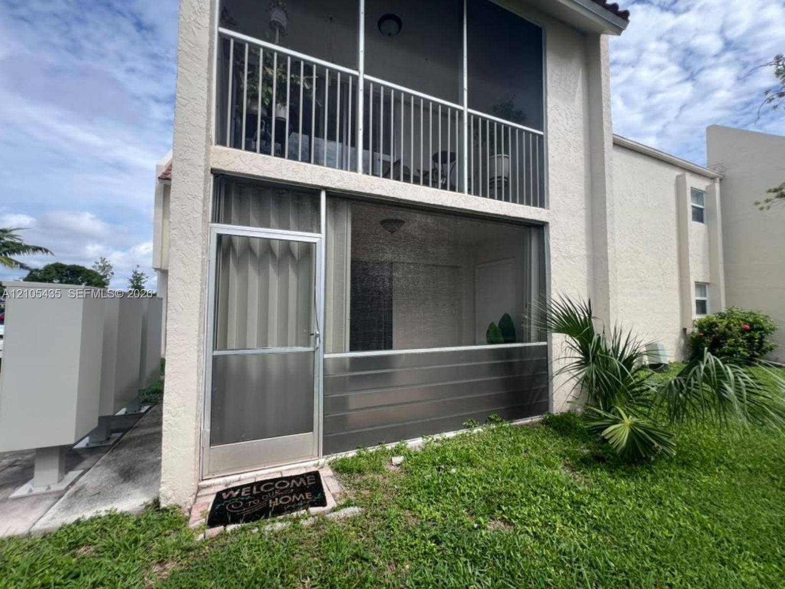 1428 SE 4th Avenue, #159, Deerfield Beach, FL 33441 Two-story residence featuring a ground-level screen-enclosed patio, a second-story screened balcony with metal railing, and a light-colored stucco exterior