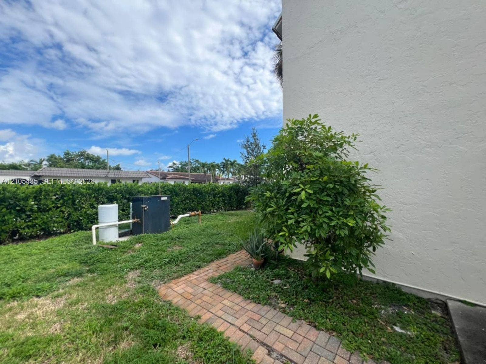1428 SE 4th Avenue, #159, Deerfield Beach, FL 33441 Side exterior featuring a stucco facade, brick paver walkway, and hedge-lined landscaping