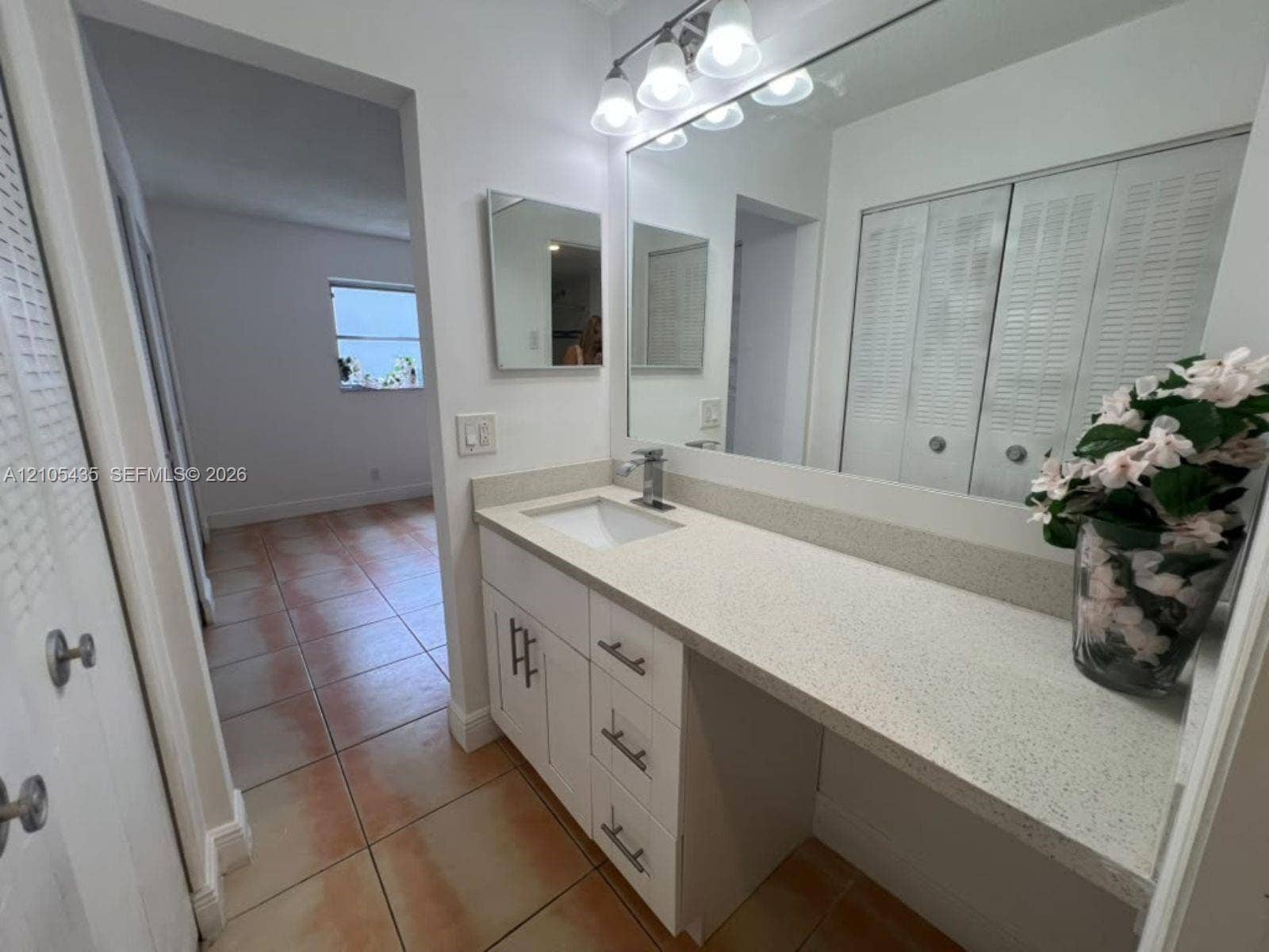 1428 SE 4th Avenue, #159, Deerfield Beach, FL 33441 Bathroom vanity featuring white cabinetry, a light-toned solid surface countertop, an undermount rectangular sink, a single-handle chrome faucet, and a large wall-mounted vanity mirror