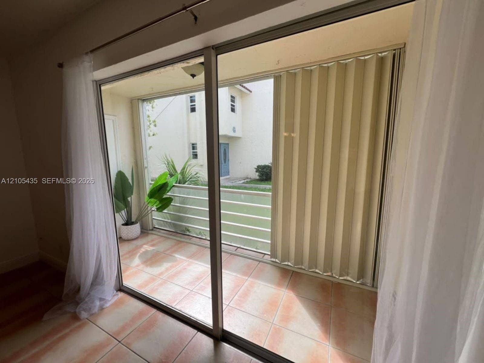 1428 SE 4th Avenue, #159, Deerfield Beach, FL 33441 Sliding glass door opening to a tiled balcony with metal railing and accordion-style shutter
