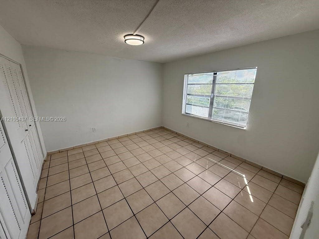 Neutral wall finishes, tile flooring, window with blinds, and a flush-mount ceiling light