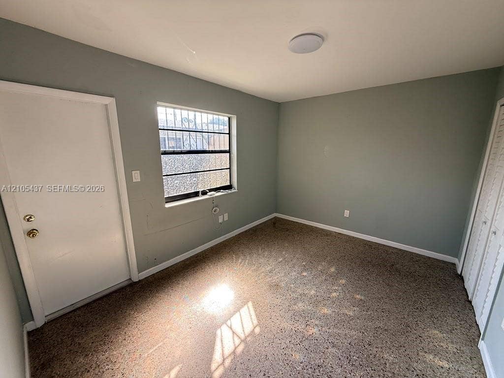 Recessed window with security bars, light gray painted walls, white trim, and a built-in closet with louvered doors