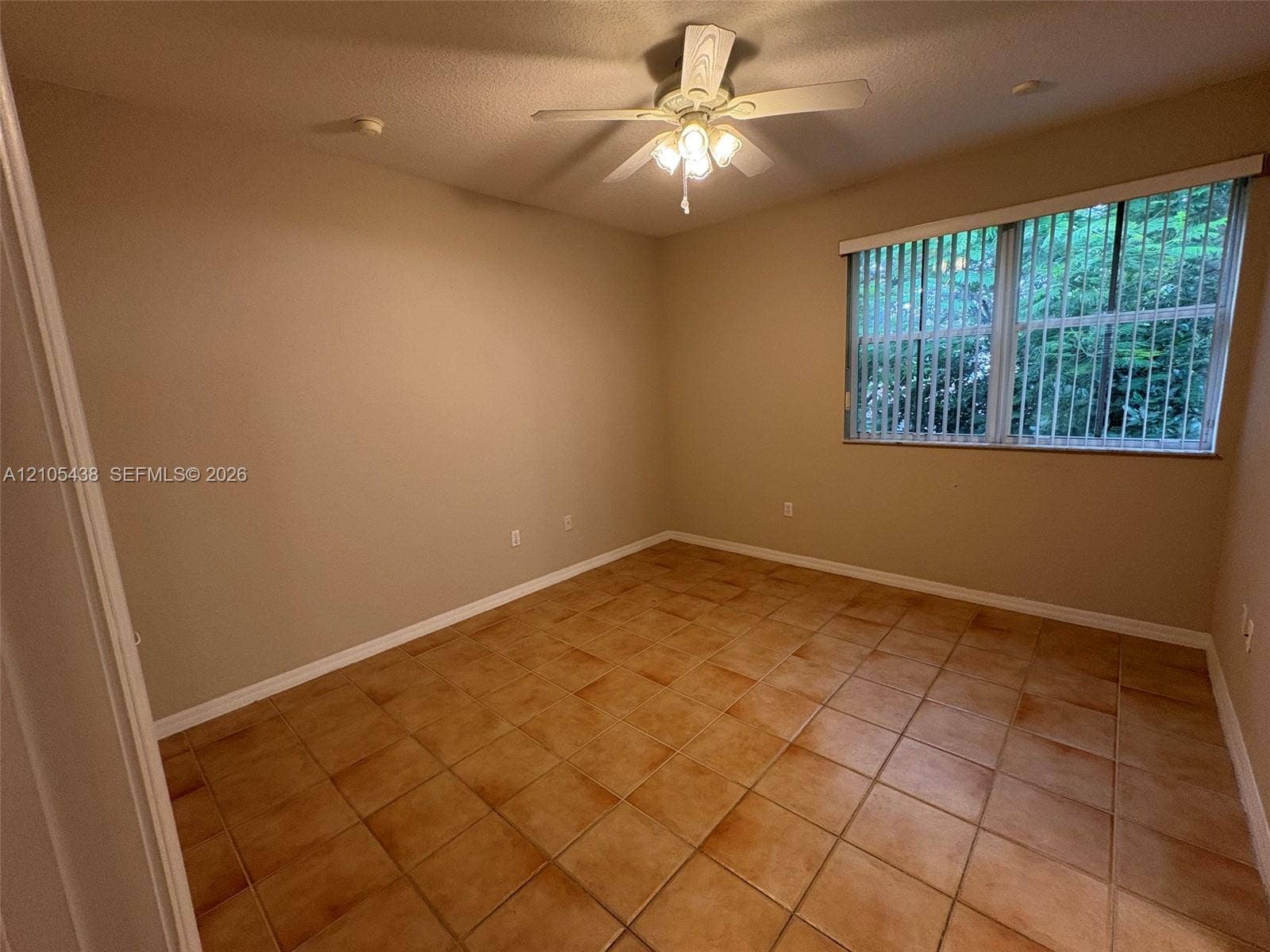 Neutral tone wall paint, tile flooring, window with vertical blinds, and a ceiling fan with integrated lighting