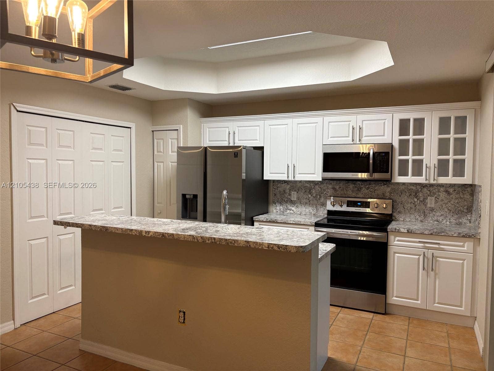 White shaker cabinetry, stainless steel appliances, granite countertops, and tile flooring