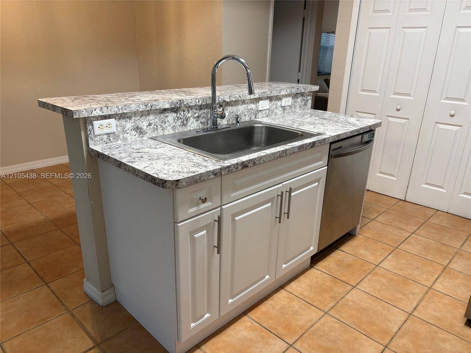 Kitchen island with a stainless steel sink, chrome gooseneck faucet, light-toned countertop, and integrated dishwasher