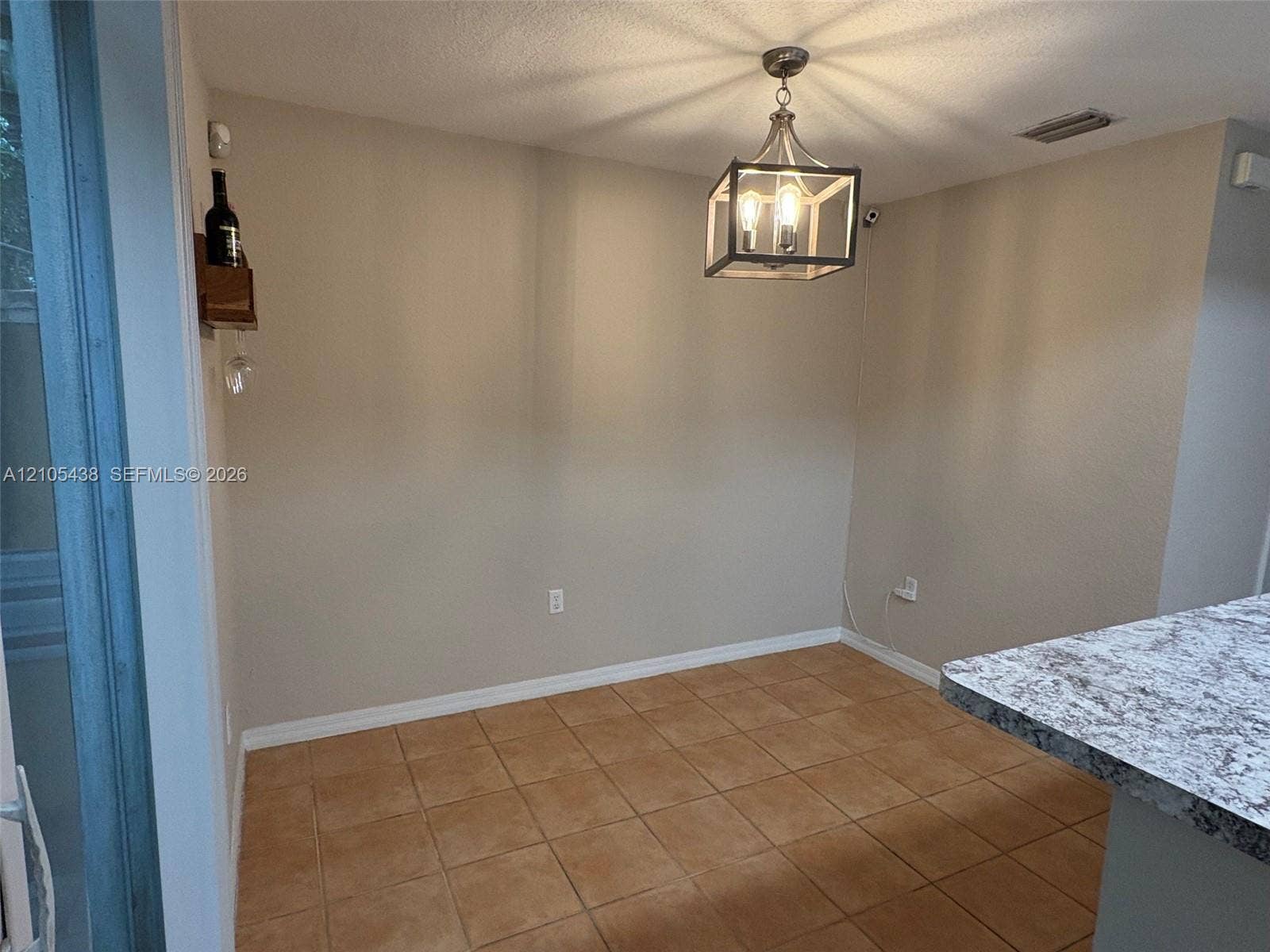 Tiled flooring, overhead chandelier, light-toned wall finish, and a granite-finish countertop