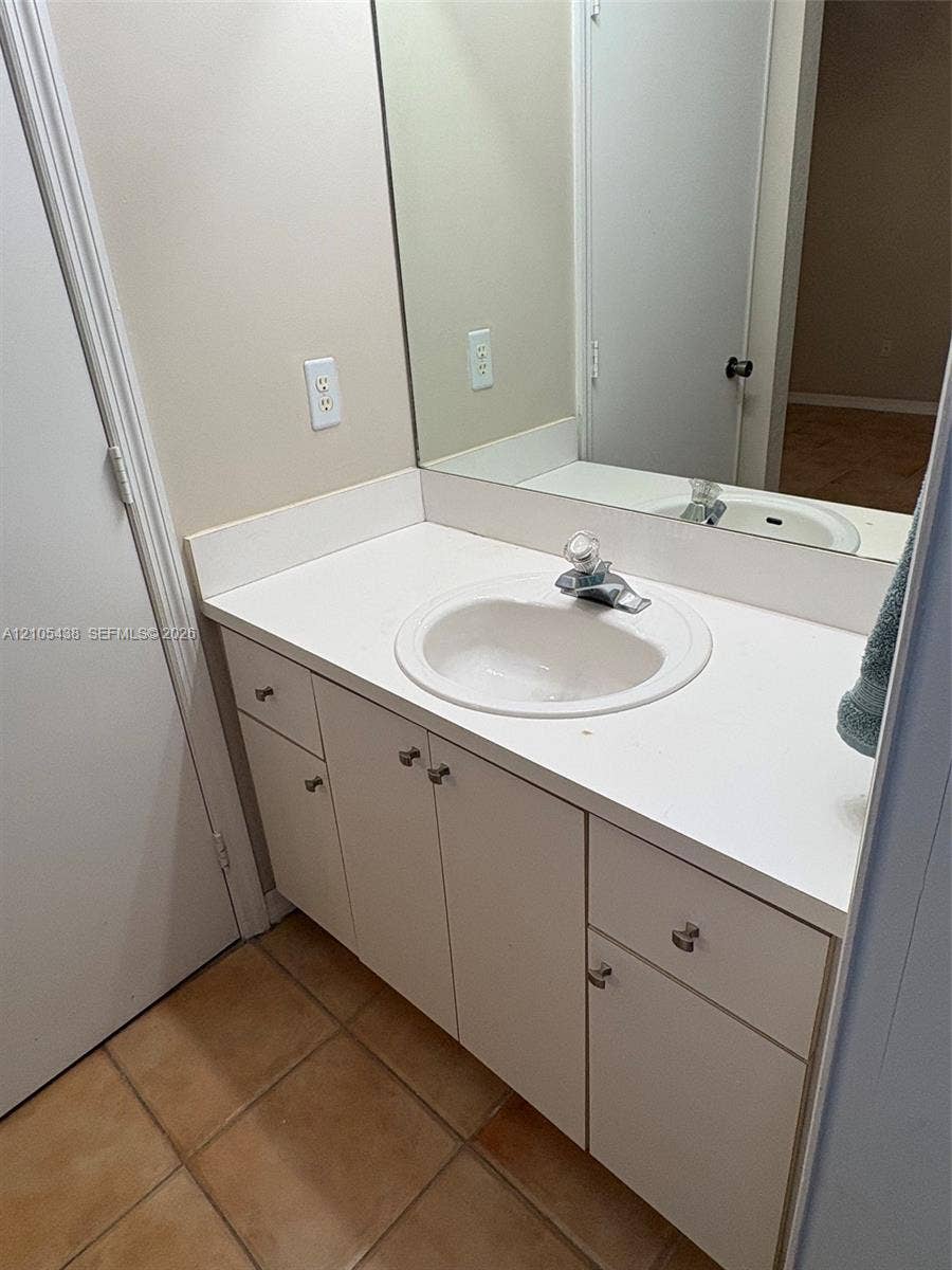 Vanity with an integrated sink and ample counter space, featuring a large wall-mounted mirror