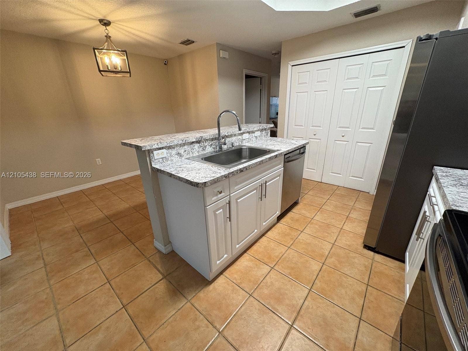 Kitchen featuring a central island with an undermount sink, a stainless steel dishwasher, and white cabinetry