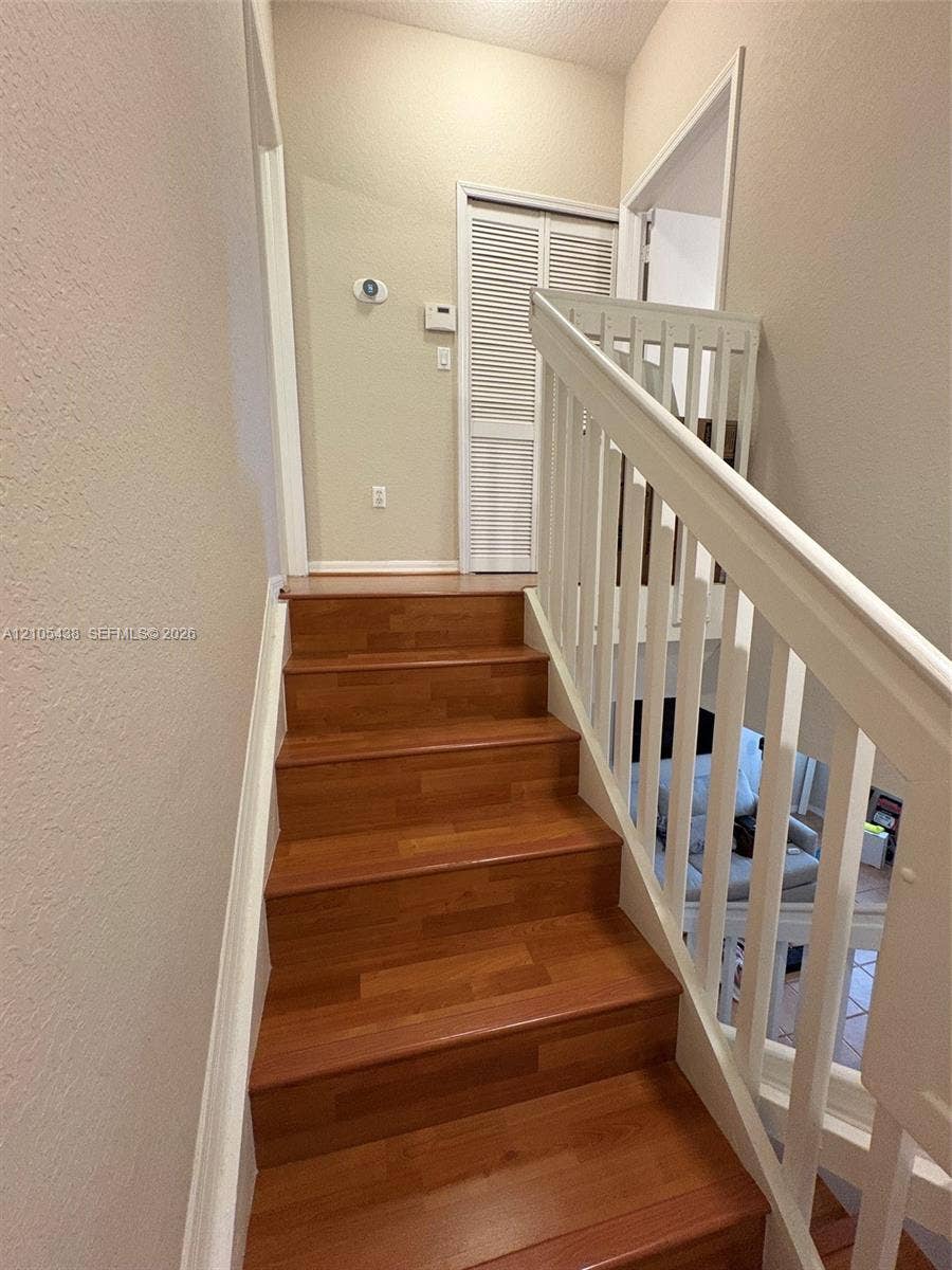 Wood-finish stairs with white risers and railing