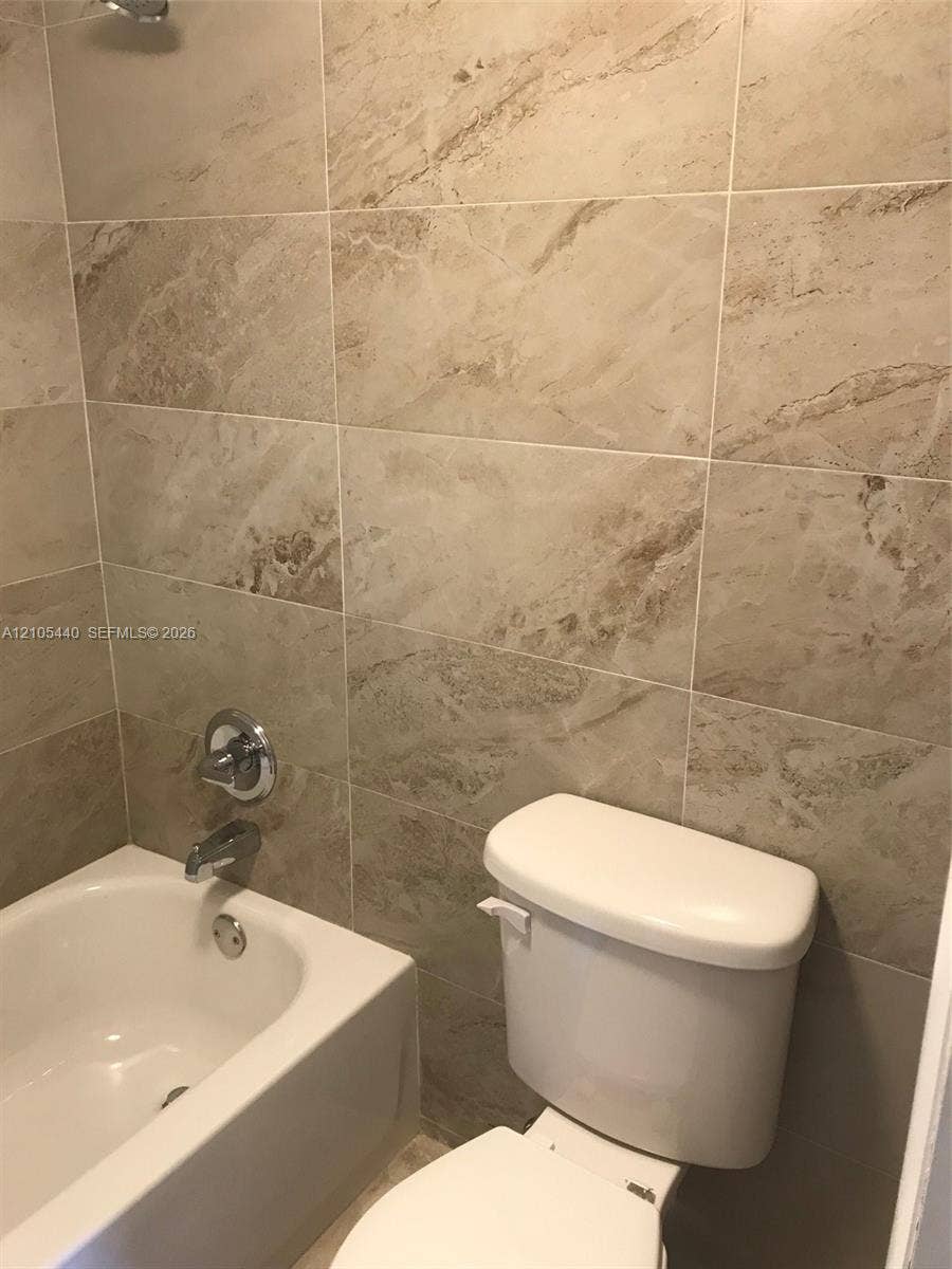 16710 NE 9th Avenue, #707, North Miami Beach, North Miami Beach, FL 33162 Bathroom featuring a built-in bathtub, chrome fixtures, and neutral-toned wall tiles