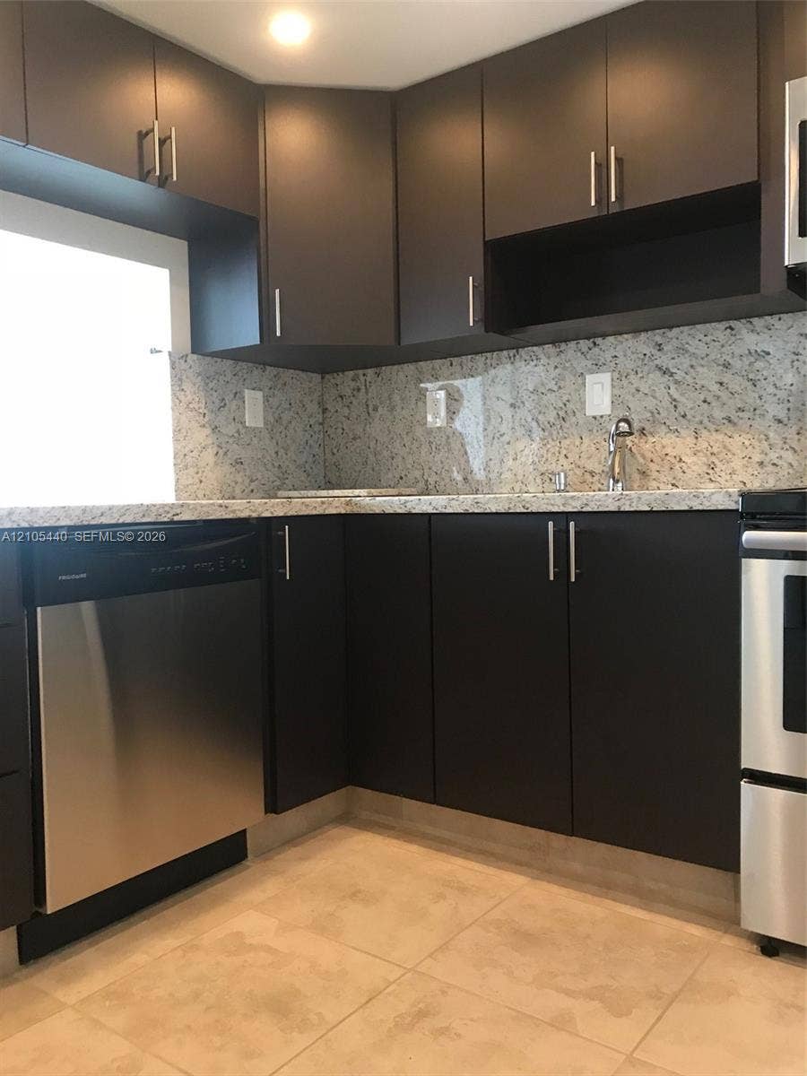 16710 NE 9th Avenue, #707, North Miami Beach, North Miami Beach, FL 33162 Dark wood-finish cabinetry with stainless steel hardware, light-toned stone-finish countertops and backsplash, stainless steel appliances, and large square floor tiles