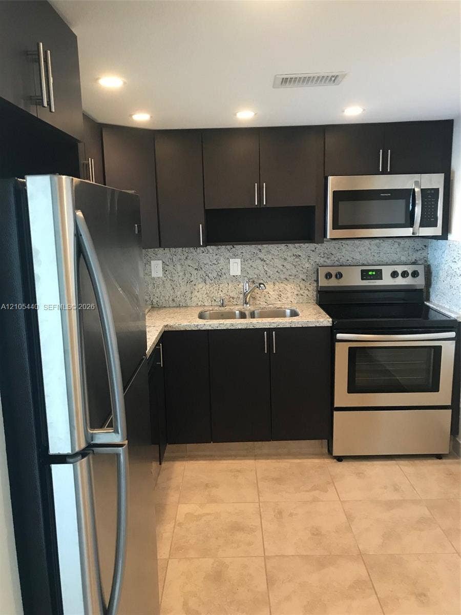 16710 NE 9th Avenue, #707, North Miami Beach, North Miami Beach, FL 33162 Kitchen featuring dark wood-finish cabinetry, light-toned tiled flooring, granite-style countertops, stainless steel appliances, and recessed lighting