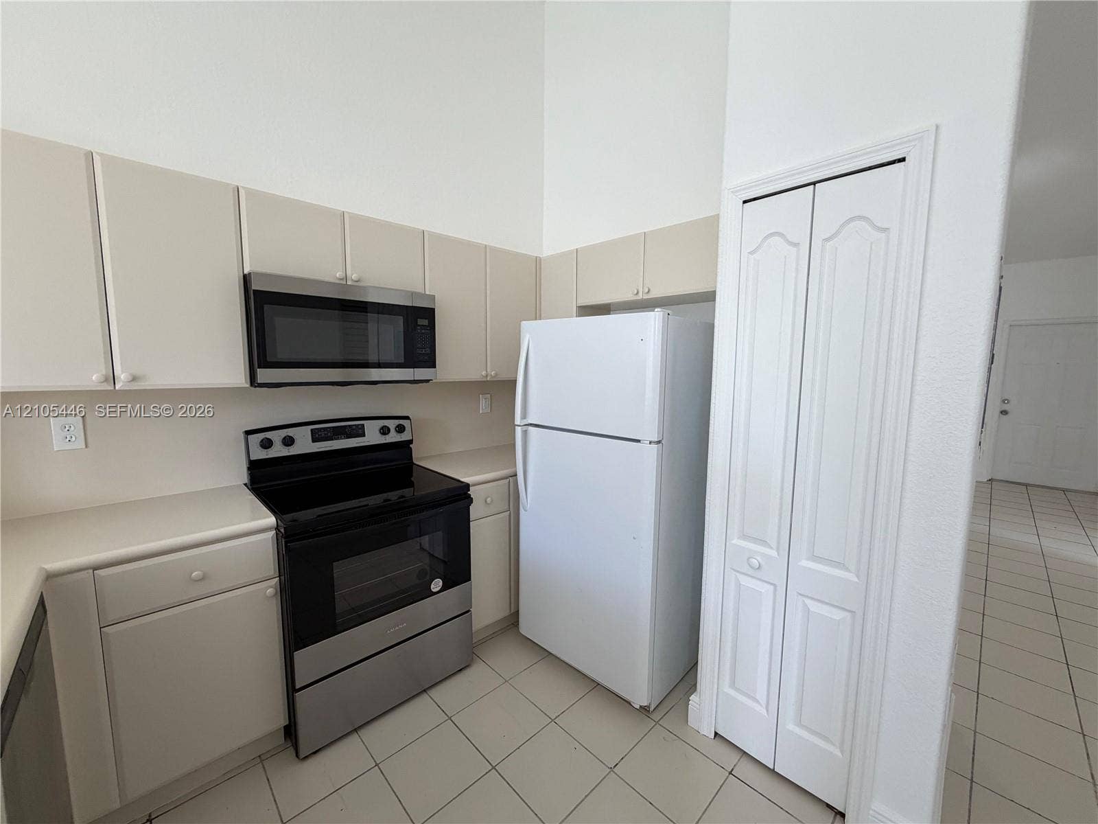 Kitchen featuring light cabinetry, a stainless steel microwave, and a black and stainless steel range