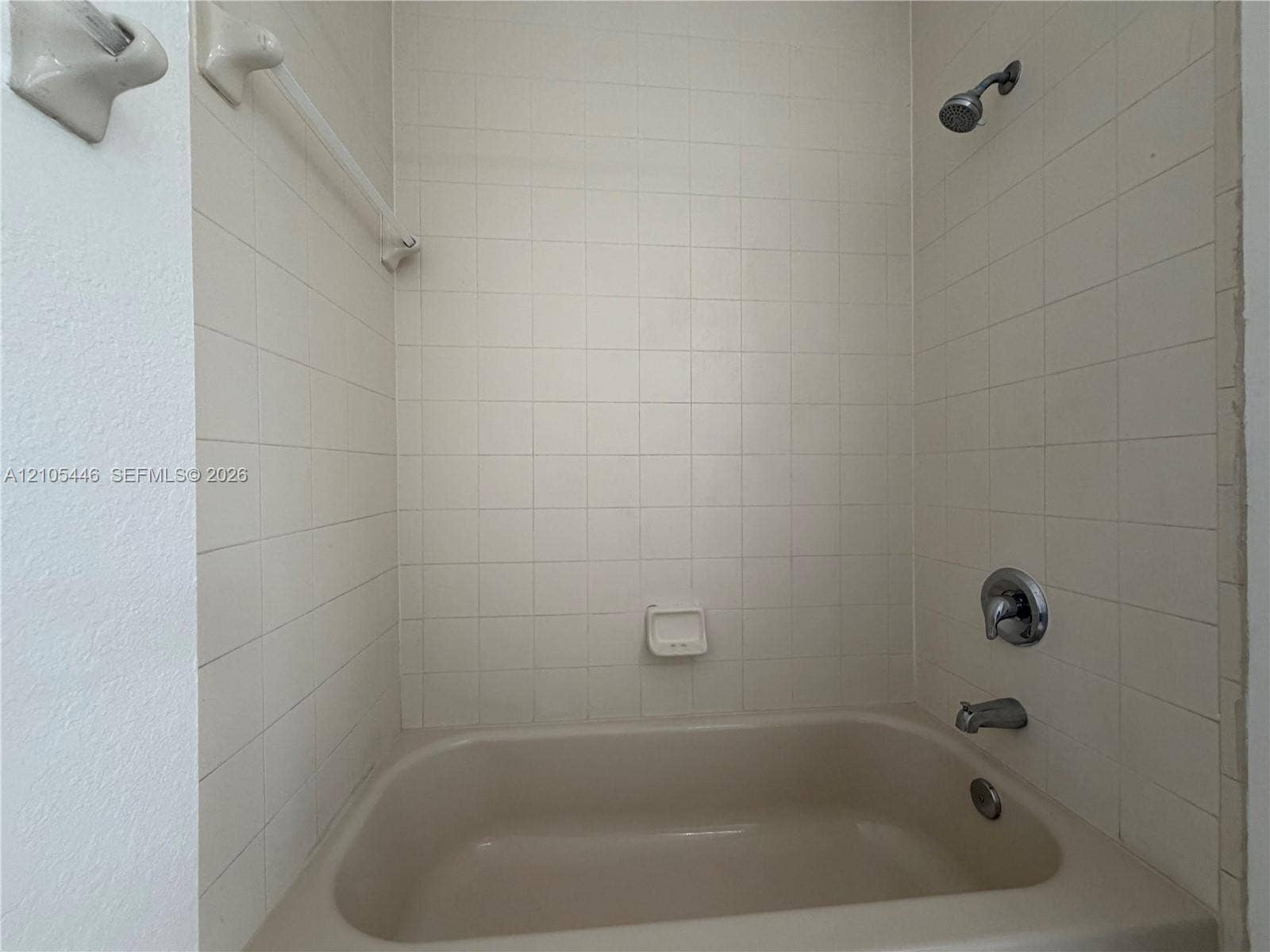 Bathtub with tiled surround, showerhead, and chrome fixtures