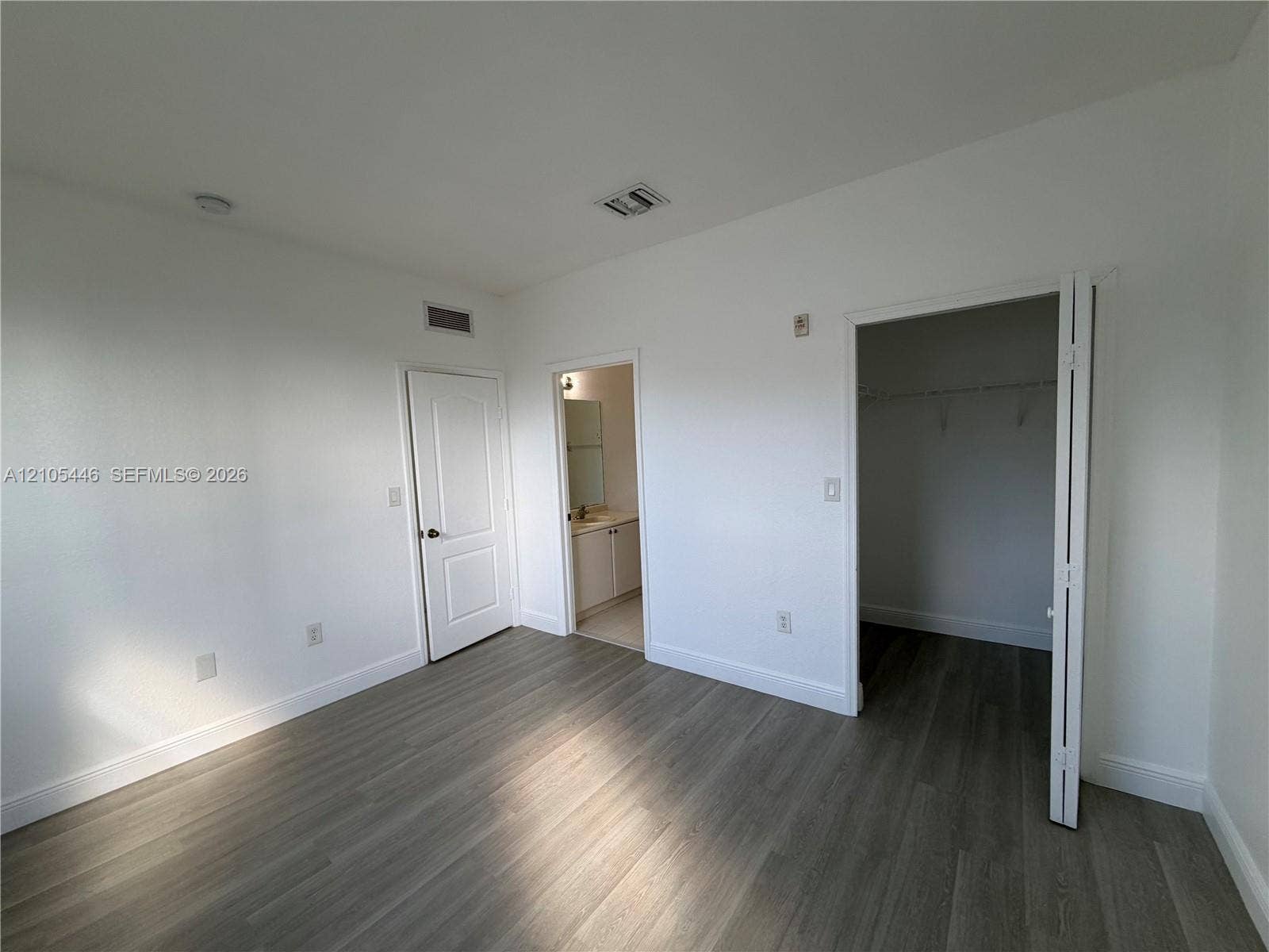Wood-finish flooring, white walls, recessed ceiling lighting, and a closet with bifold doors