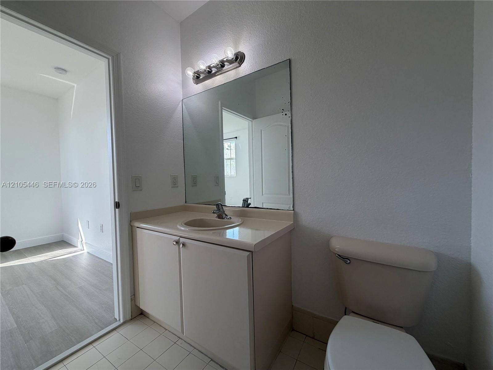 Vanity with integrated sink, two-door cabinetry, and an overhead light bar