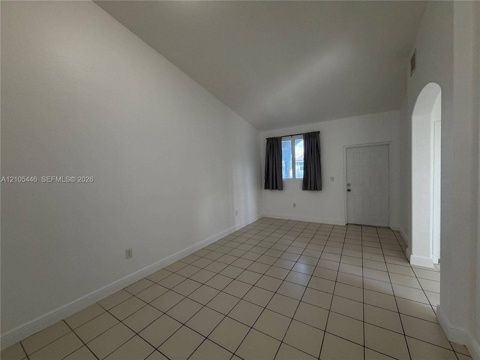 Tiled flooring throughout with a window featuring dark curtains, and a white door