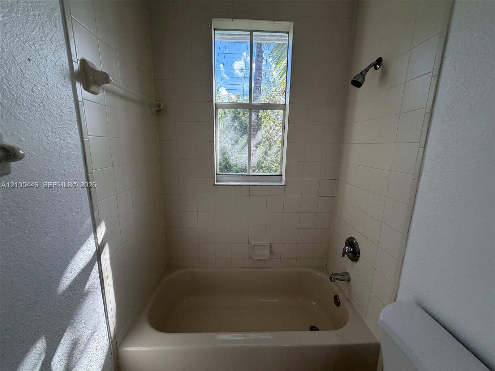Bathtub with tile surround, a window, and chrome fixtures