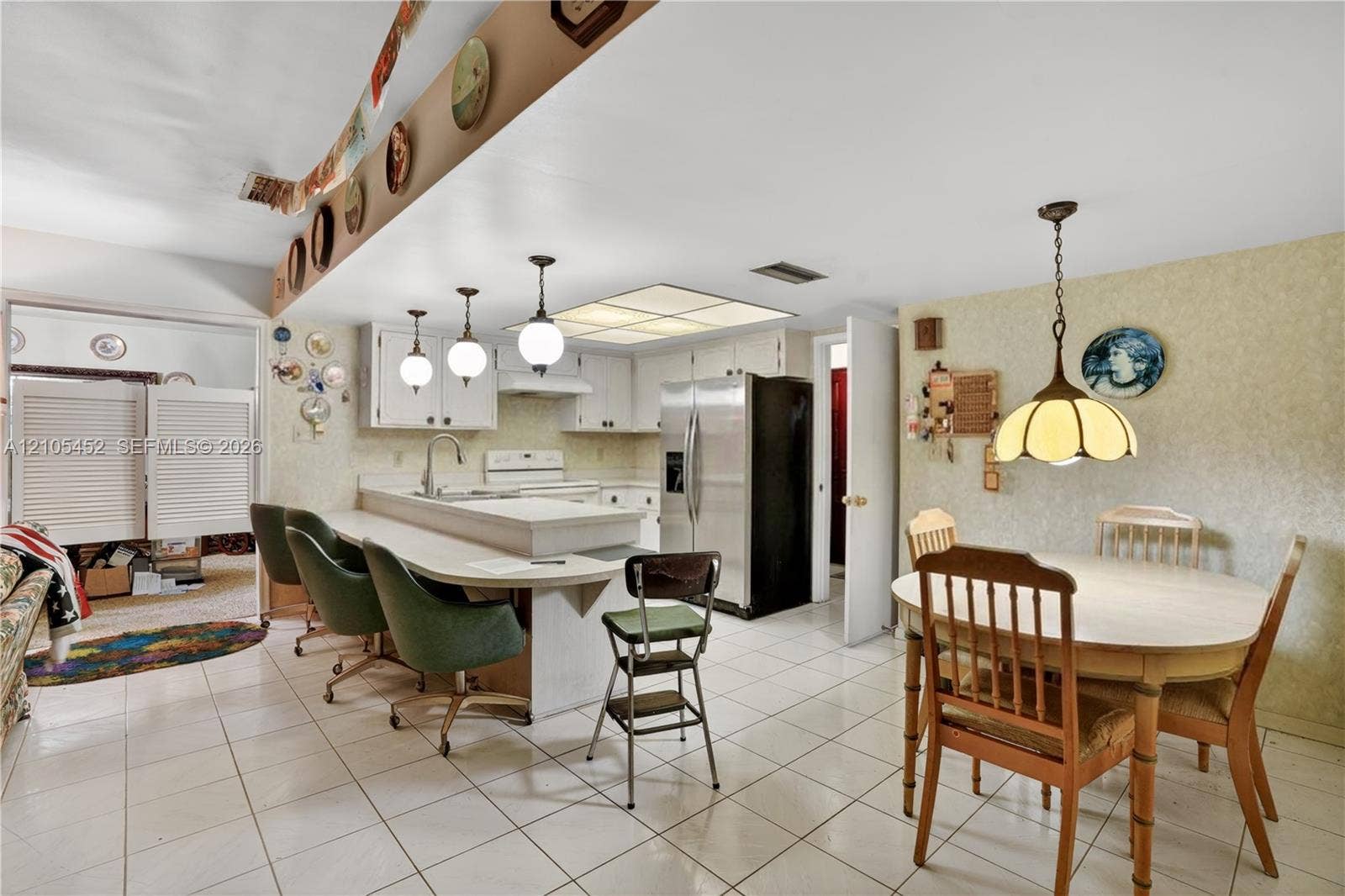 Kitchen featuring a tiered peninsula with a breakfast bar, white cabinetry, tile flooring, recessed ceiling lighting, and three pendant lights