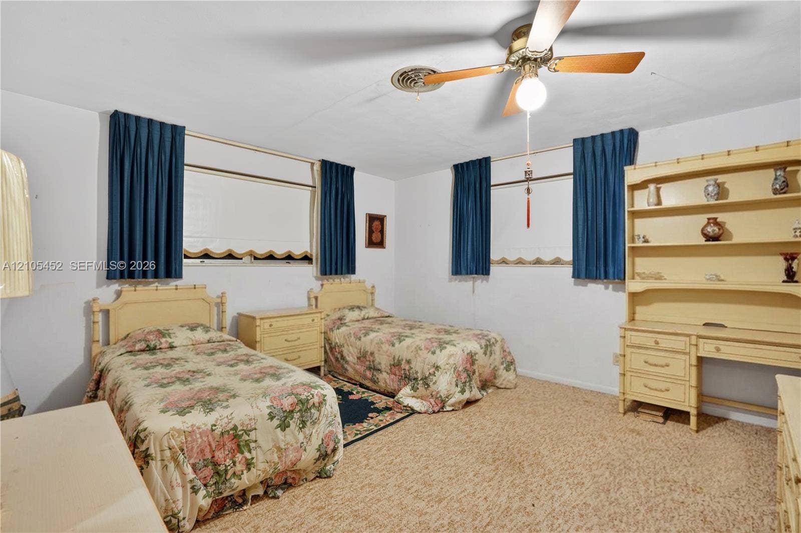 Built-in wall cabinetry with shelving and integrated desk, textile flooring, and ceiling fan with light fixture
