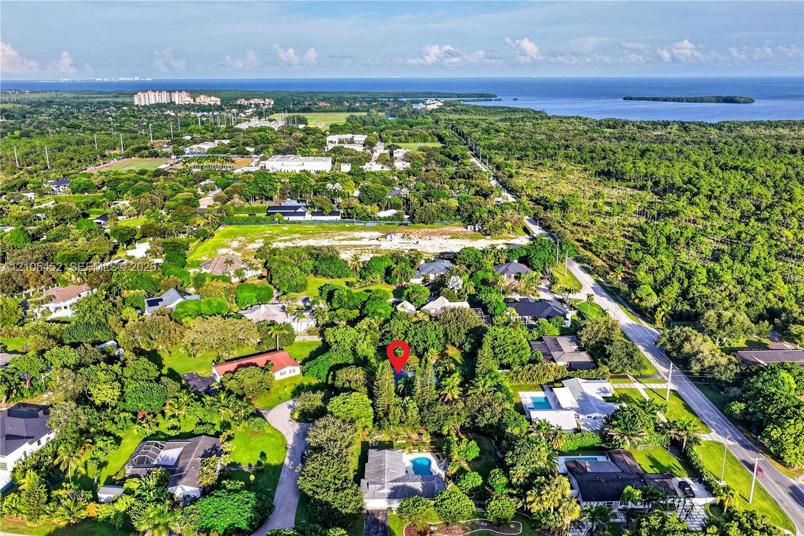 Aerial perspective of a residential property surrounded by mature tree canopy and proximity to coastal waters
