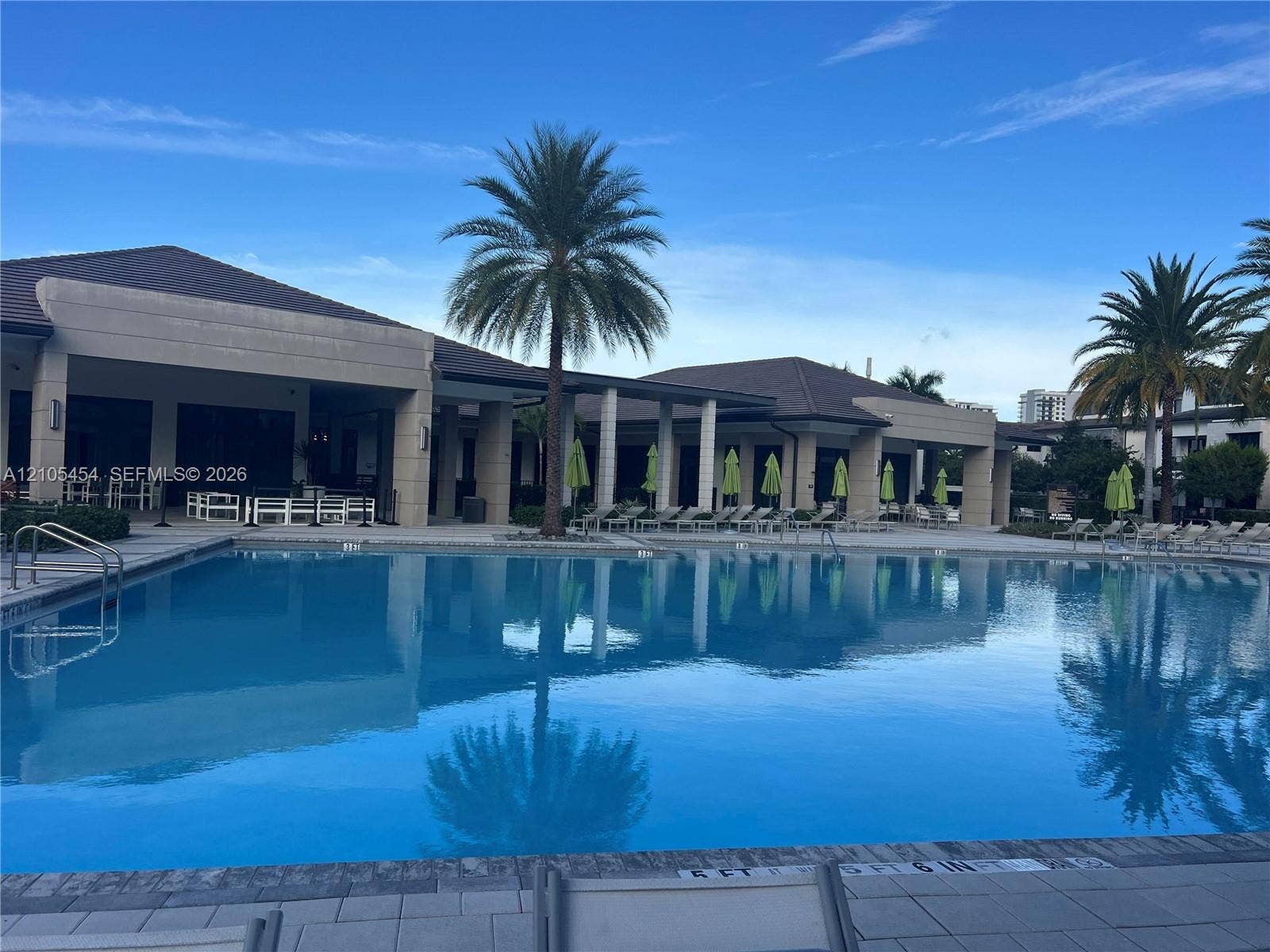 4745 NW 84th Court, #20, Doral, FL 33166 Expansive outdoor pool with integrated steps, surrounded by a paved deck and a covered patio area with recessed lighting