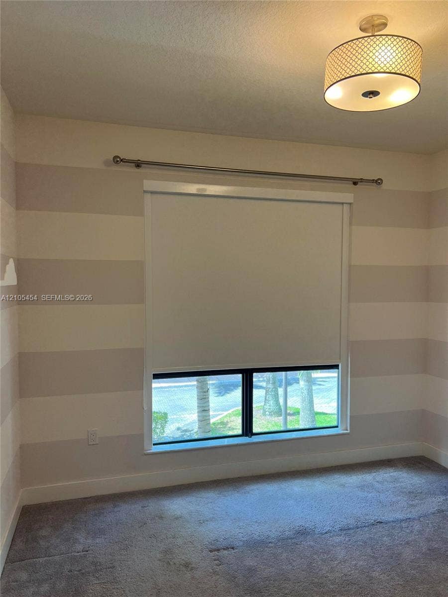 4745 NW 84th Court, #20, Doral, FL 33166 Striped wall treatment, carpeted flooring, window with roller shade, ceiling-mounted light fixture, and window rod