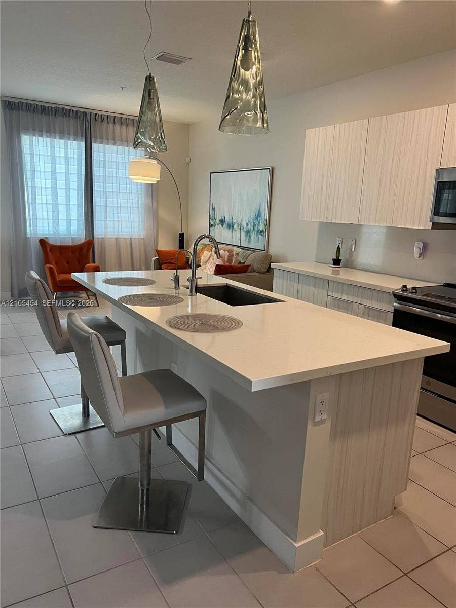 4745 NW 84th Court, #20, Doral, FL 33166 Kitchen island with integrated sink, white countertops, and modern pendant lighting