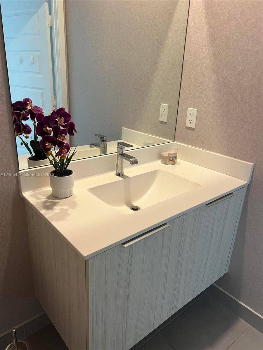 4745 NW 84th Court, #20, Doral, FL 33166 Floating vanity with light wood-finish cabinetry, integrated rectangular sink, and polished chrome faucet