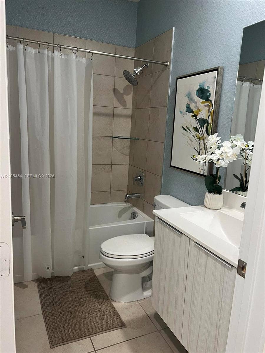 4745 NW 84th Court, #20, Doral, FL 33166 Ceramic tile flooring, tub and shower combination with tiled surround, white vanity with integrated sink, and wall-mounted mirror