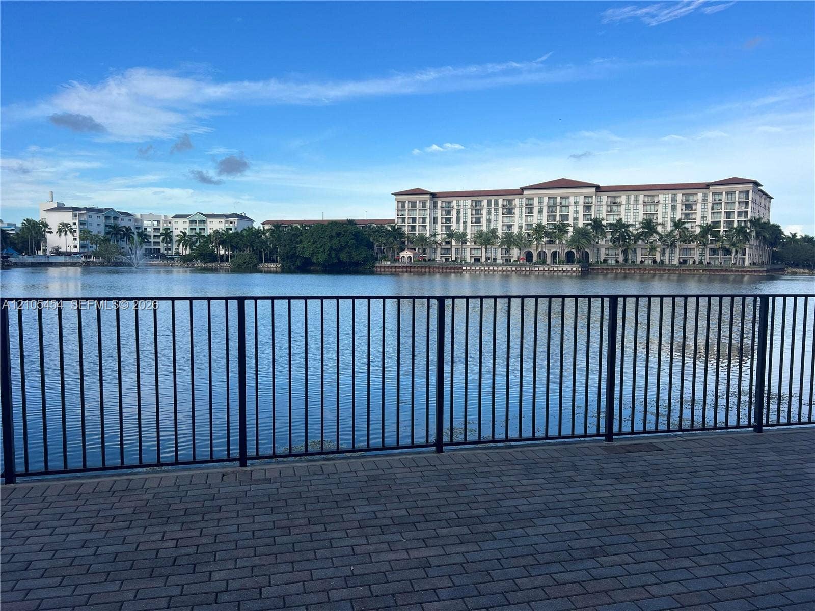 4745 NW 84th Court, #20, Doral, FL 33166 Paved waterfront promenade with metal railing overlooking the water and distant multi-story buildings