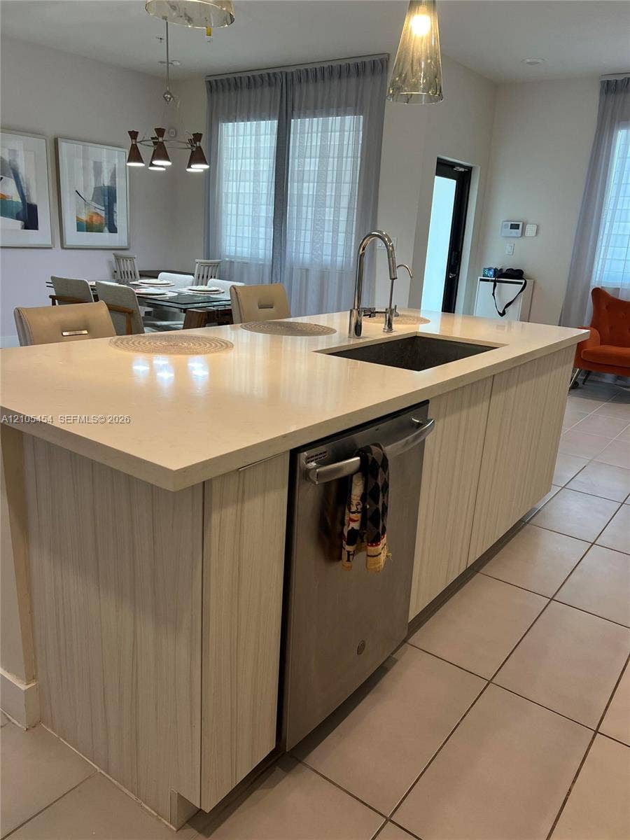 4745 NW 84th Court, #20, Doral, FL 33166 Kitchen island featuring a single-basin sink, gooseneck faucet, integrated dishwasher, and light-toned cabinetry