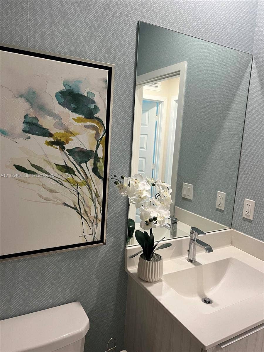 4745 NW 84th Court, #20, Doral, FL 33166 Vanity with integrated sink, polished chrome faucet, and expansive wall mirror
