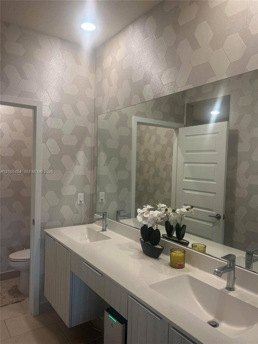 4745 NW 84th Court, #20, Doral, FL 33166 Dual vanity with integrated sinks, modern wall-mounted cabinetry, expansive mirror, and recessed lighting
