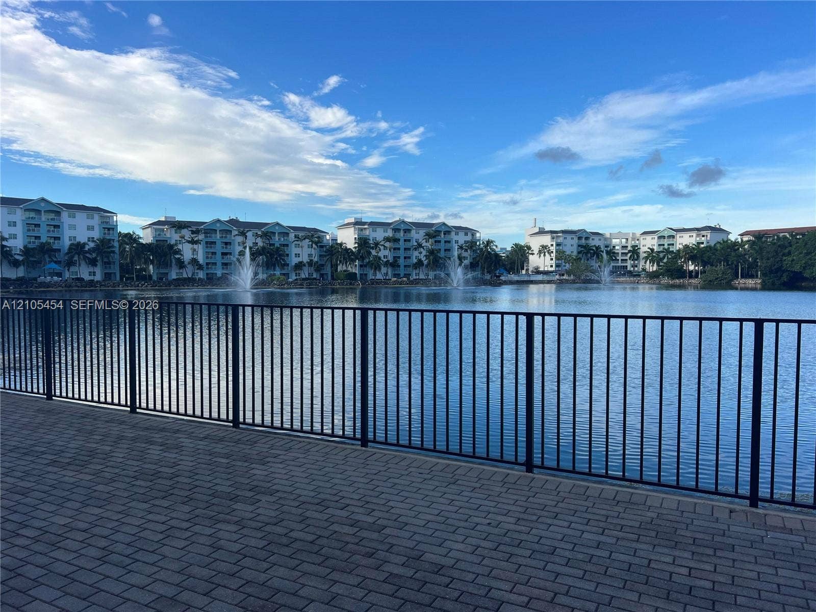 4745 NW 84th Court, #20, Doral, FL 33166 Paver patio with black metal railing overlooking a tranquil lake with water features