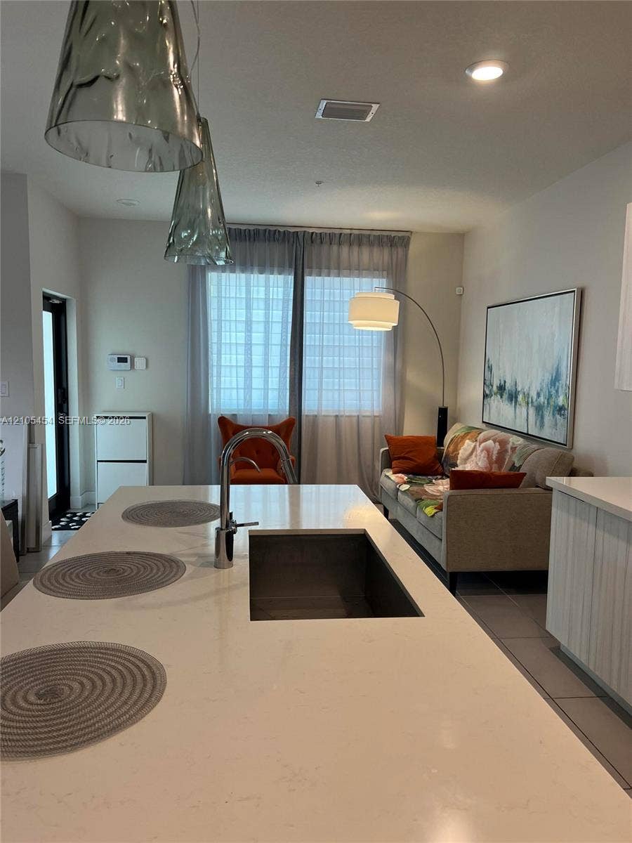 4745 NW 84th Court, #20, Doral, FL 33166 Kitchen island featuring a built-in undermount sink with a gooseneck faucet