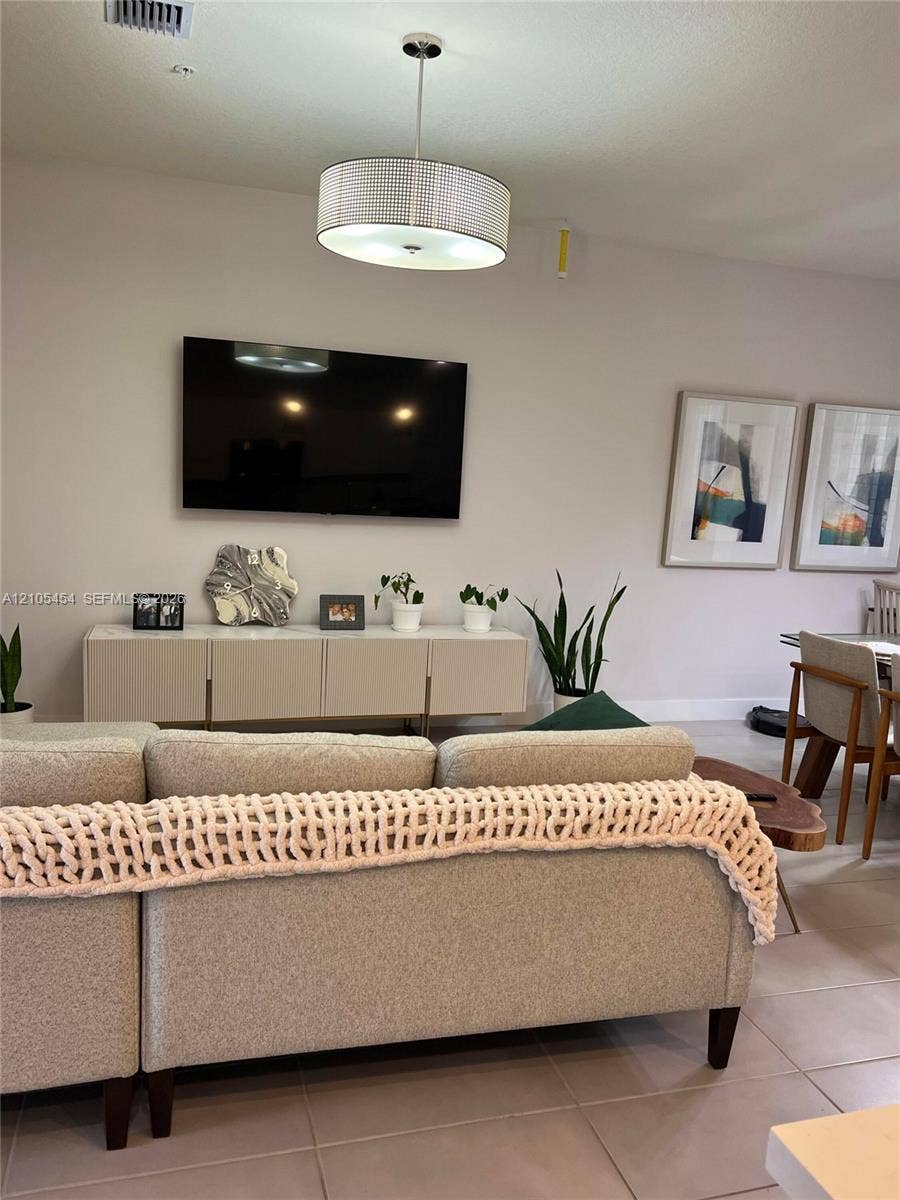 4745 NW 84th Court, #20, Doral, FL 33166 Vaulted ceiling with a contemporary drum pendant light fixture, wall-mounted television, and a floating console cabinet