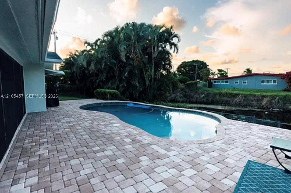 1083 SW 25th Avenue, Boynton Beach, FL 33426 Backyard area featuring a stone-paver patio, in-ground swimming pool, and mature palm trees
