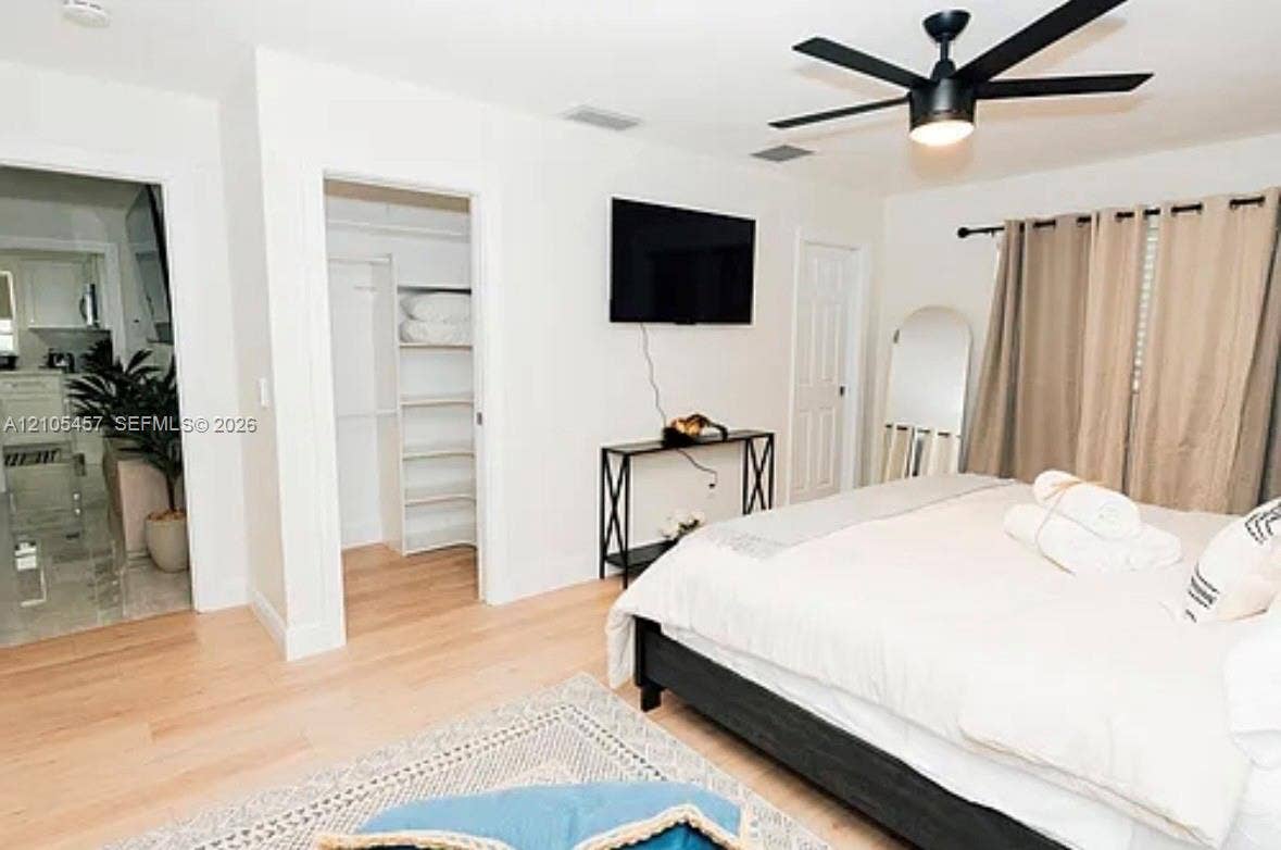 1083 SW 25th Avenue, Boynton Beach, FL 33426 Room featuring wood-finish flooring, a matte black ceiling fan, and a walk-in closet with built-in shelving