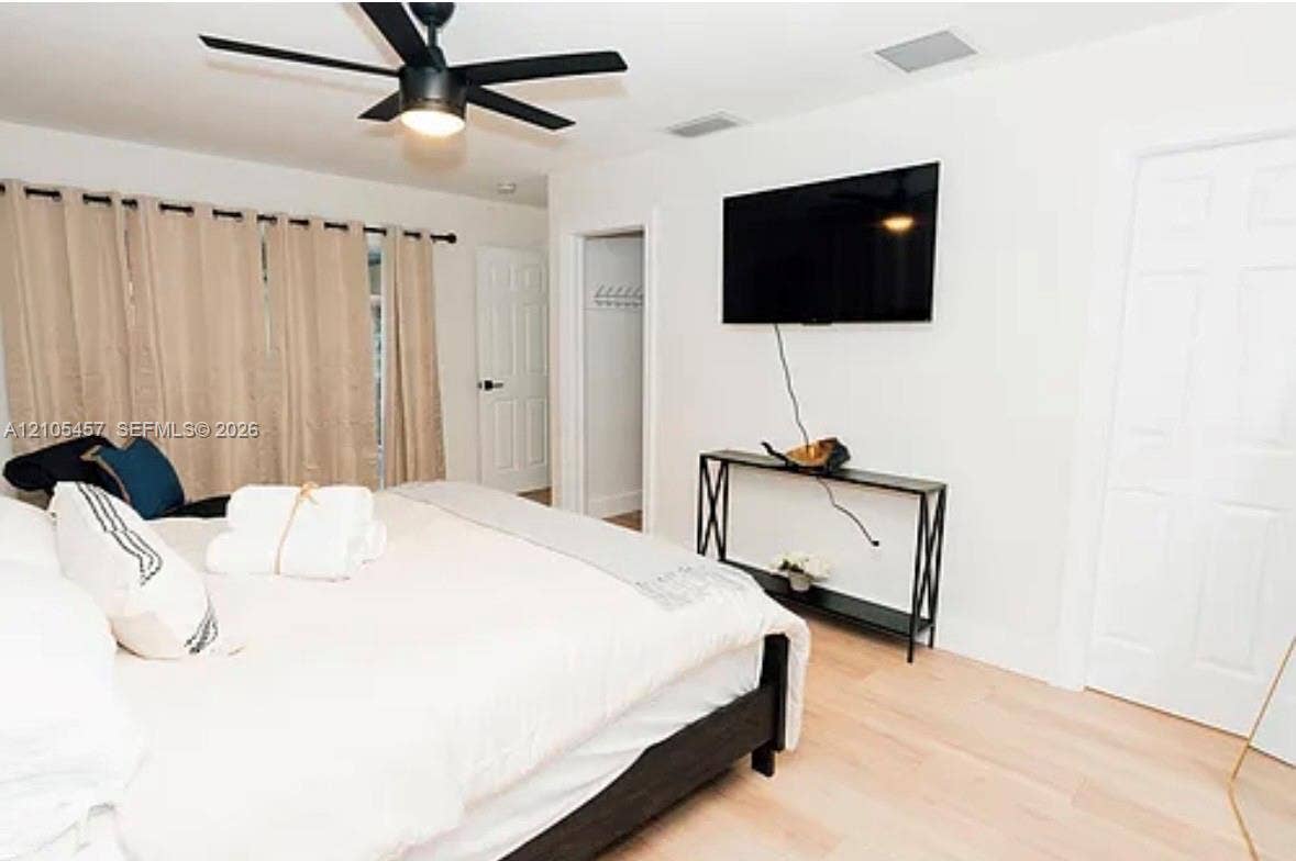 1083 SW 25th Avenue, Boynton Beach, FL 33426 Bedroom featuring light-tone wood-finish flooring, matte black ceiling fan with integrated lighting, and white six-panel interior doors