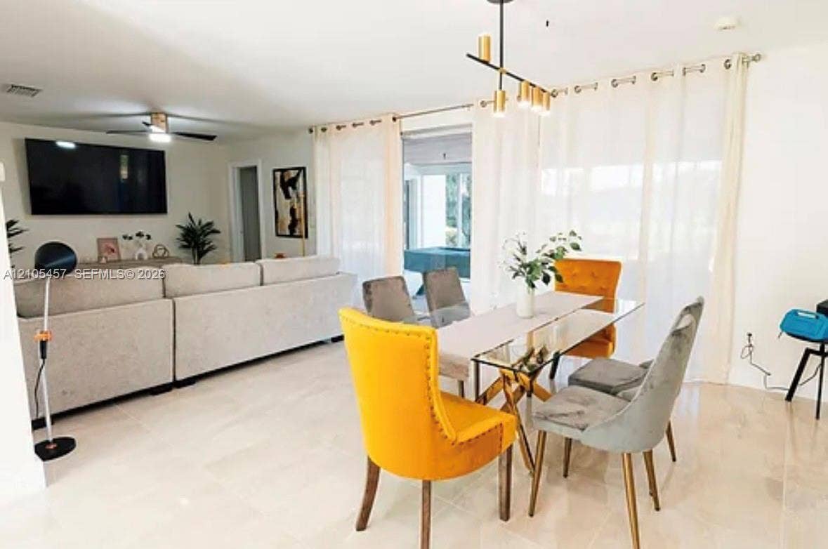 1083 SW 25th Avenue, Boynton Beach, FL 33426 Open-concept living space featuring large-format tile flooring, a multi-light linear pendant fixture, and a ceiling fan