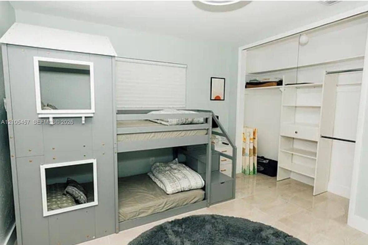 1083 SW 25th Avenue, Boynton Beach, FL 33426 Interior room featuring light-toned tile flooring, neutral wall paint, and a sliding-door closet with built-in shelving