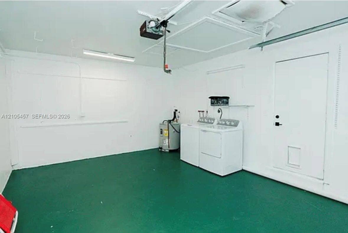 1083 SW 25th Avenue, Boynton Beach, FL 33426 Garage space featuring painted concrete flooring, white walls, overhead lighting, an automated door opener system, and a dedicated laundry area
