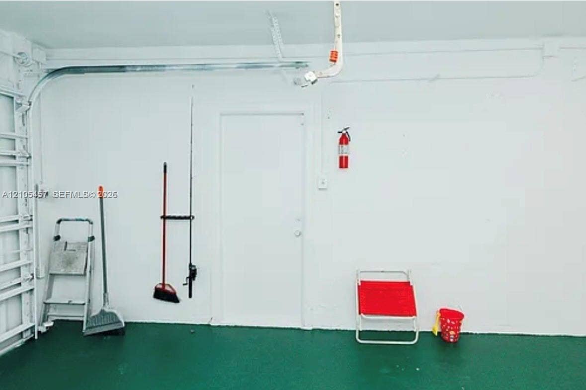 1083 SW 25th Avenue, Boynton Beach, FL 33426 Garage interior featuring painted walls, solid-surface flooring, and a wall-mounted fire extinguisher